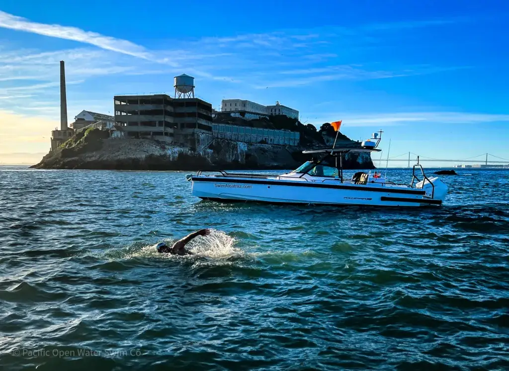 Marathon swimmer and escort vessel passing Alcatraz Island in San Francisco Bay