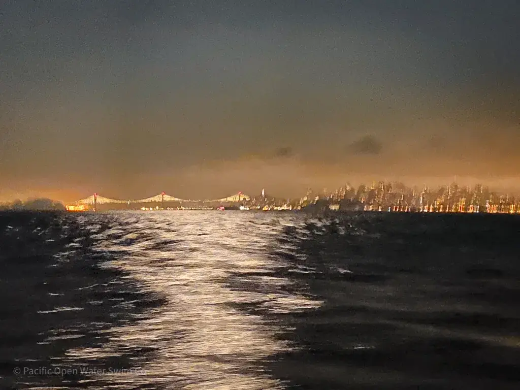 Night view from an escort vessel showing the Bay Bridge and San Francisco skyline before a Round Trip Angel Island marathon swim