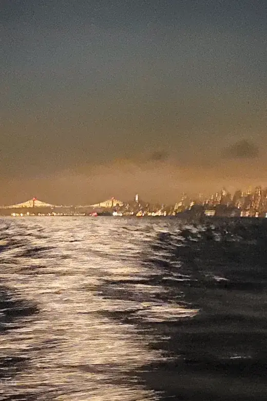 Night view from an escort vessel showing the Bay Bridge and San Francisco skyline before a Round Trip Angel Island marathon swim