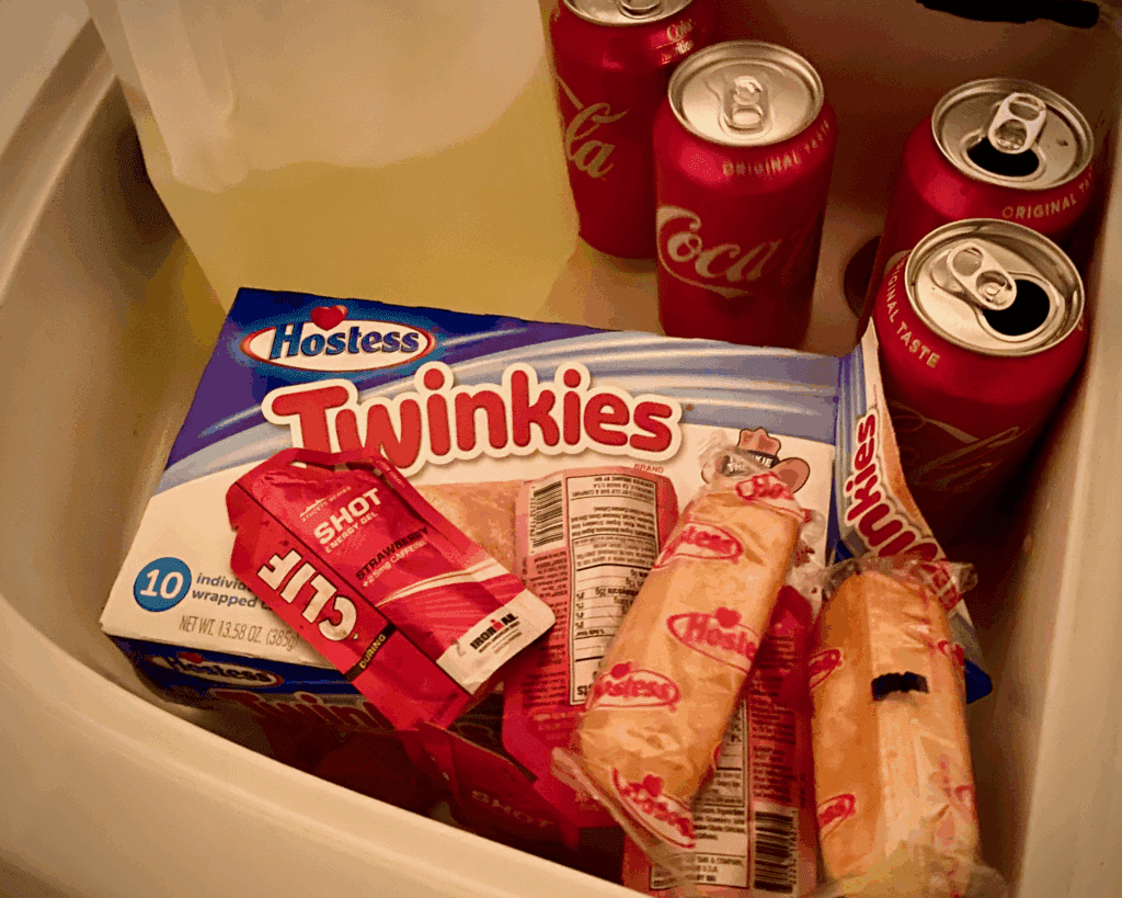 Twinkies, strawberry Clif Shots, and cans of Coca Cola arranged as marathon swim feeds