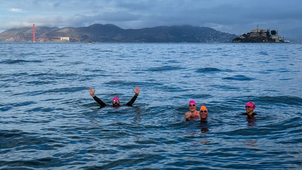 Swimmers with Alcatraz and the Golden Gate Bridge in the background.