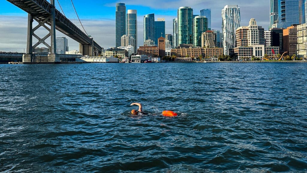 Swimmer completing the Bridge to Bridge swim under the San Francisco - Oakland Bay Bridge with the cityfront in the background.